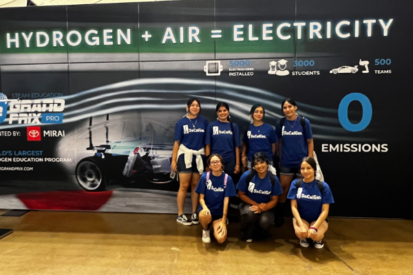 Team of 7 participates posing for a photo in front of a wall or the event