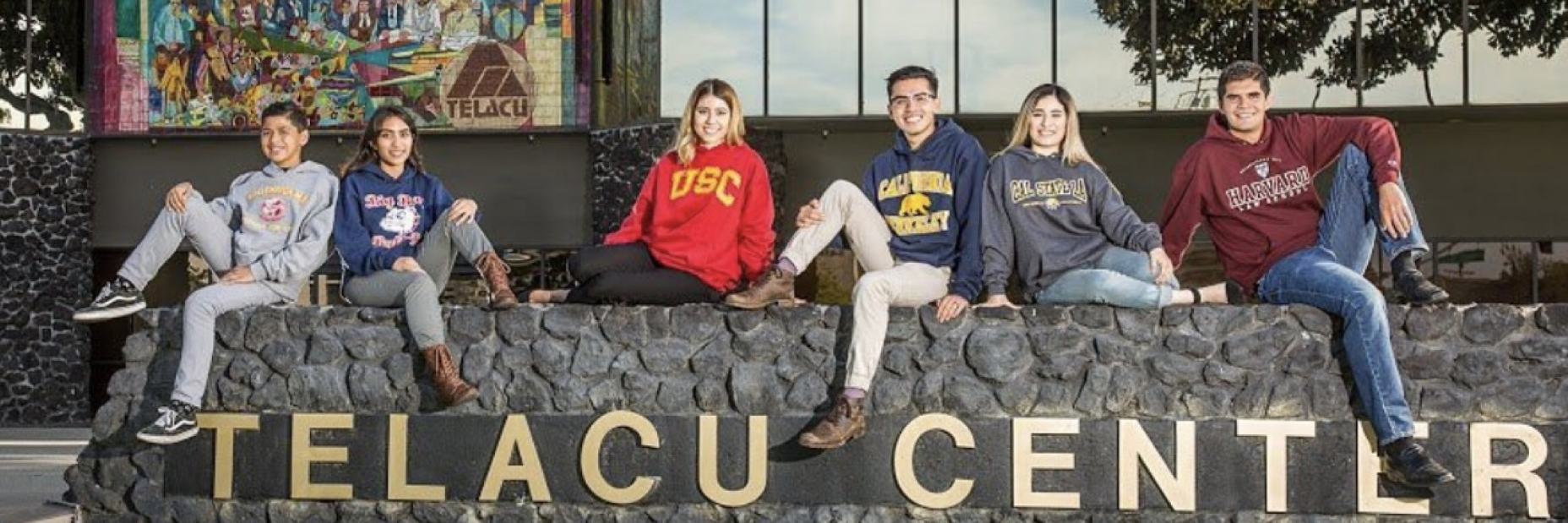 Students posing on the ledge about the TELACU CENTER lettering