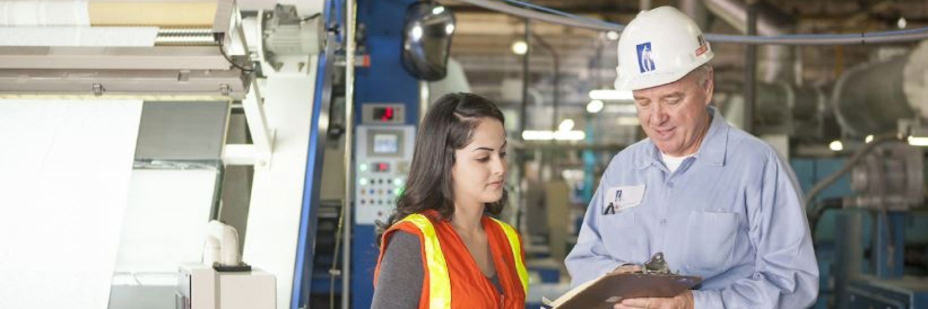 Two workers looking at a clipboard in a manufacturing setting