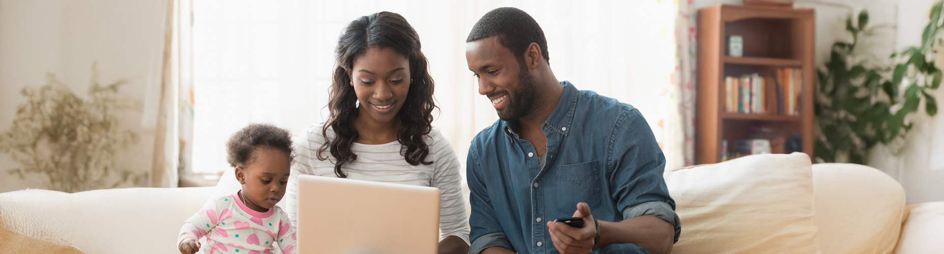 family smiling near laptop on couch