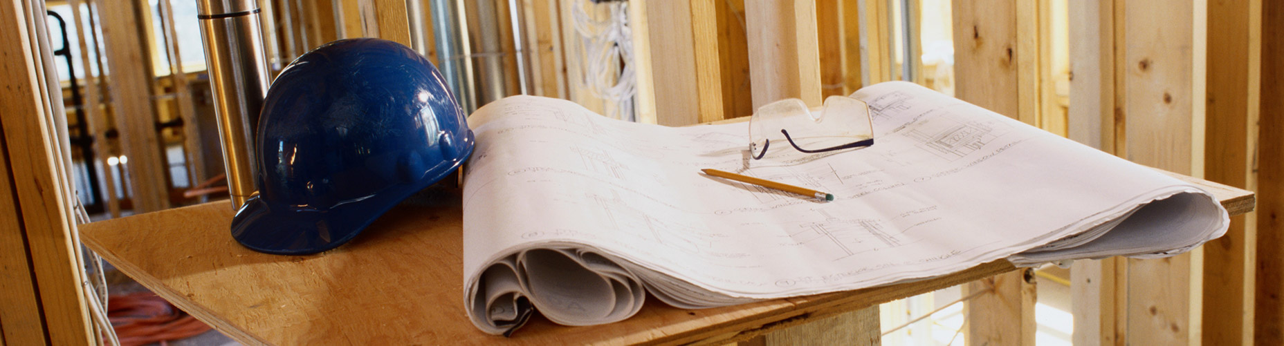 Image of hardhat and blueprints at a construction site