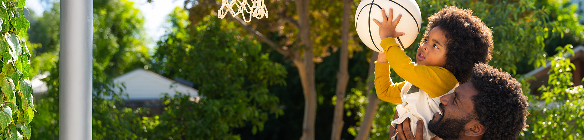 Father assisting son to dunk a basketball