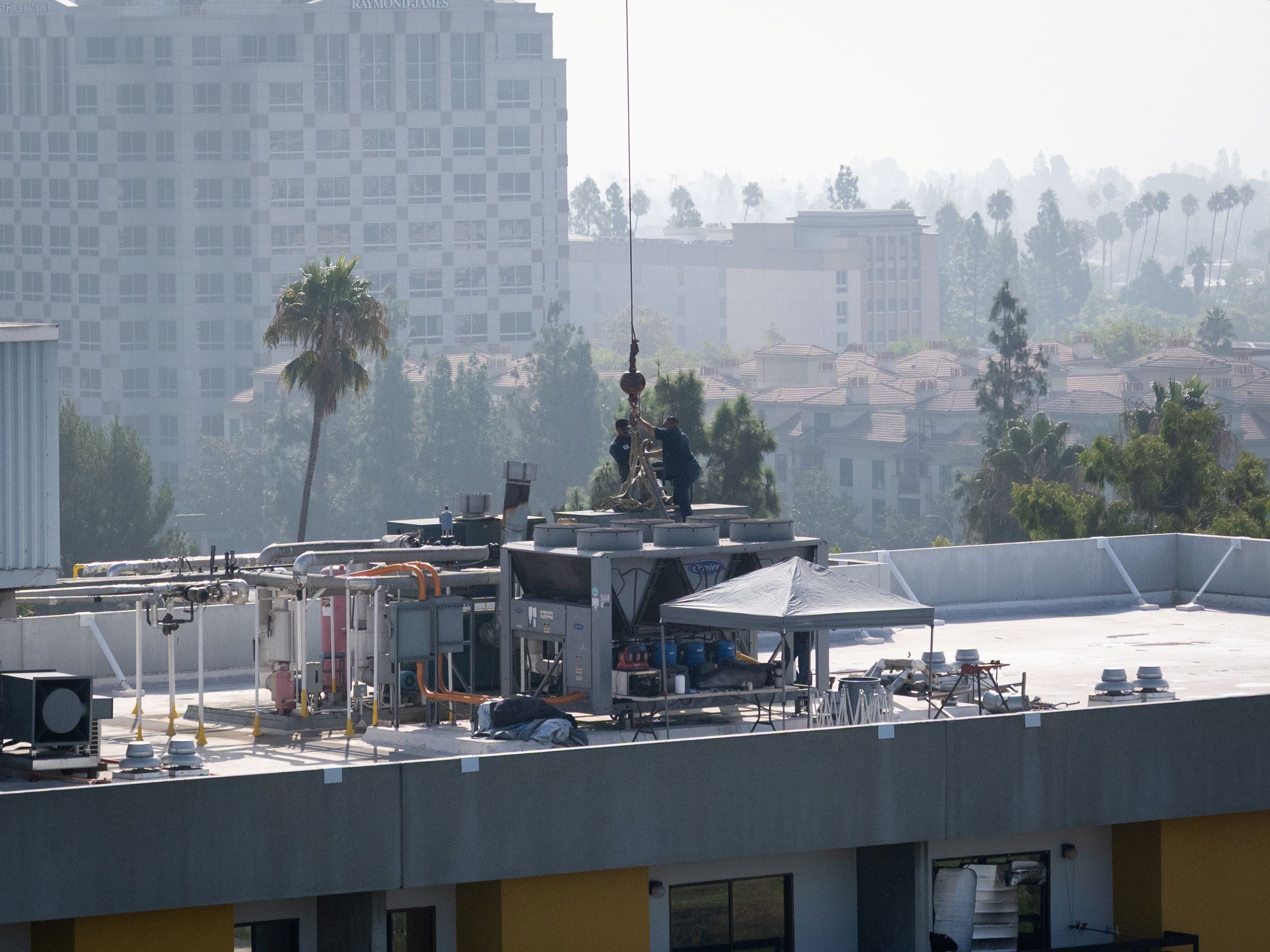 Workers loading boiler onto rooftop