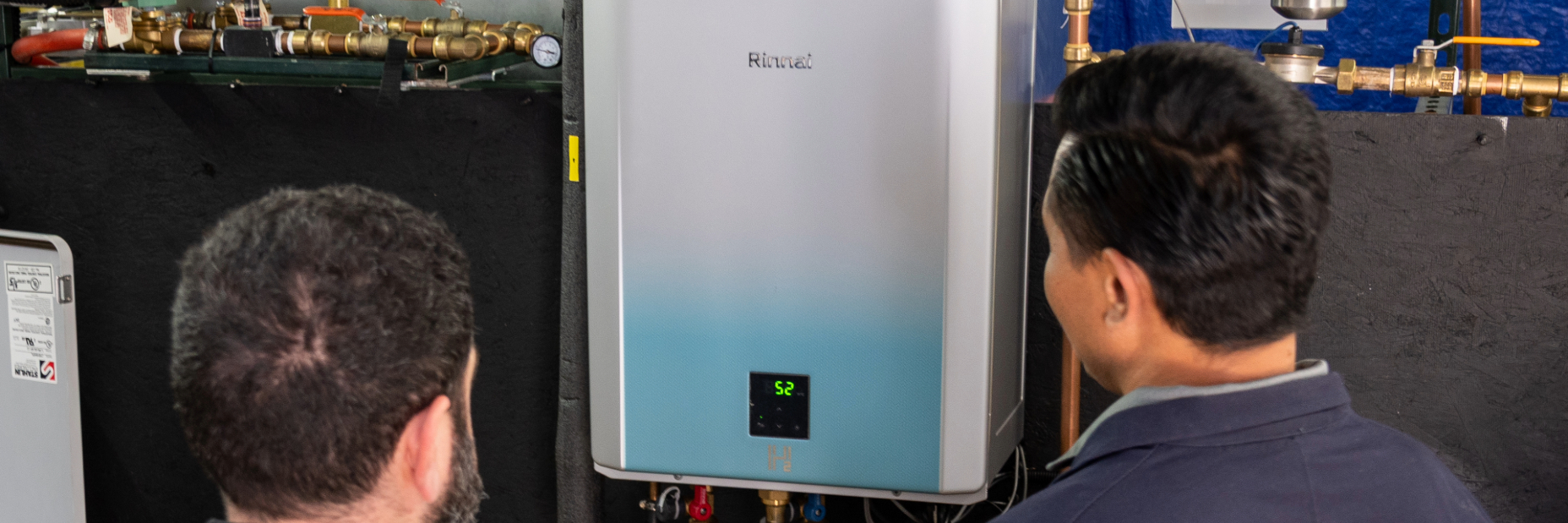 Two men looking at a tankless water heater. 