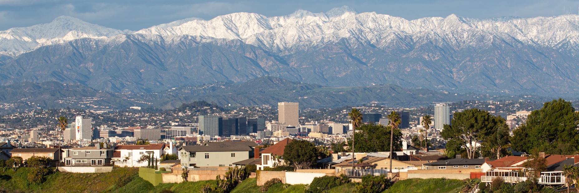 image of buildings in the foreground and snow capped mountains in the background