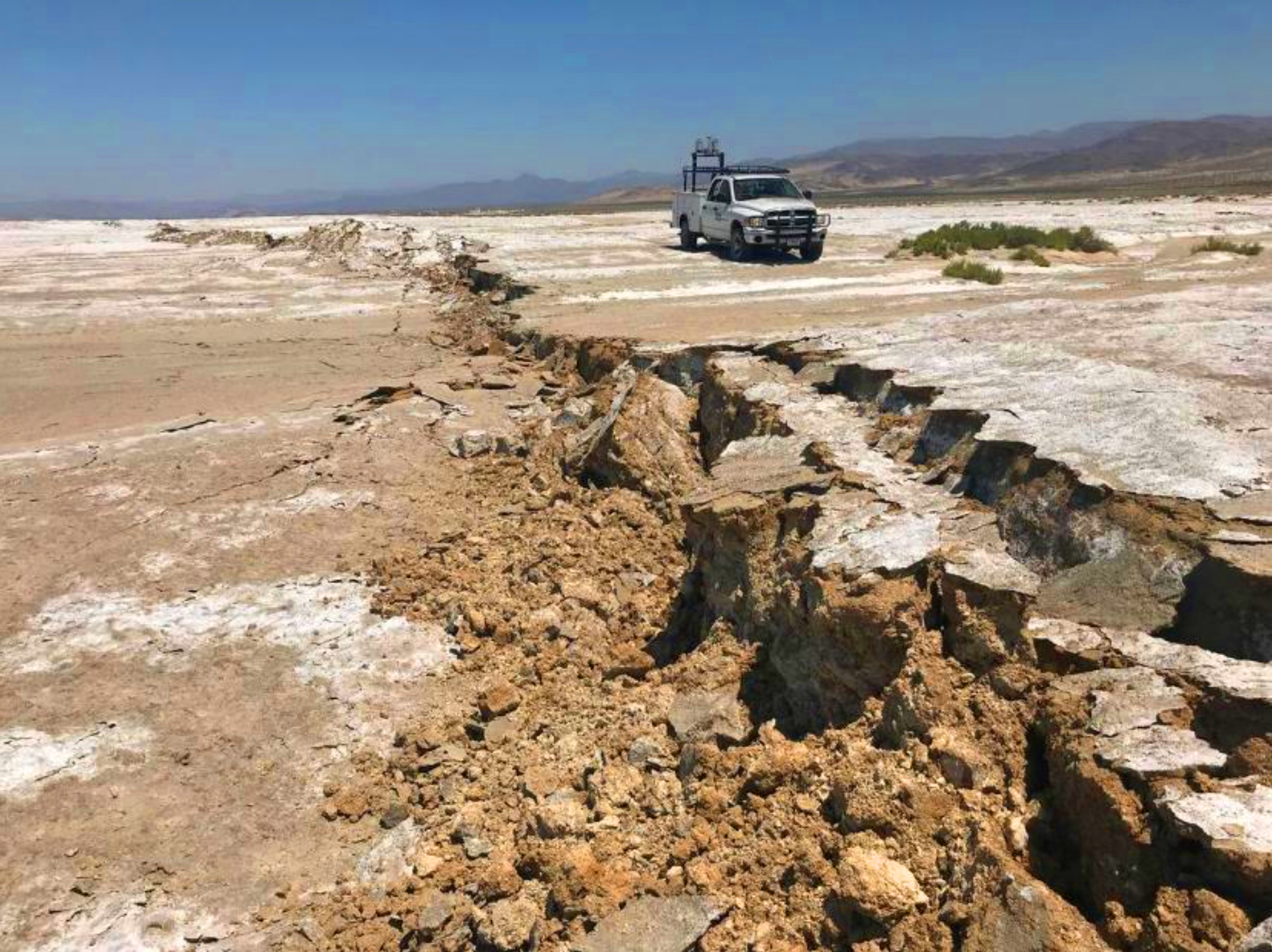 Photo of rupture of Earth's surface and a pickup truck.