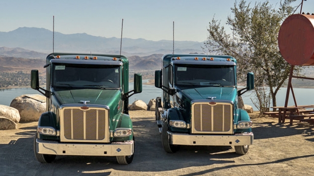 two trucks side by side with a view of hills and a lake