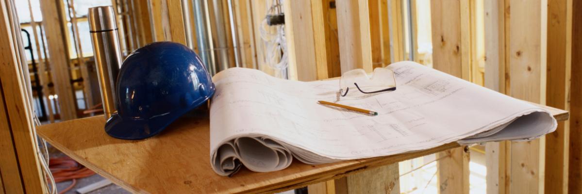 a hard hat and safety glasses on the table inside a home being built.