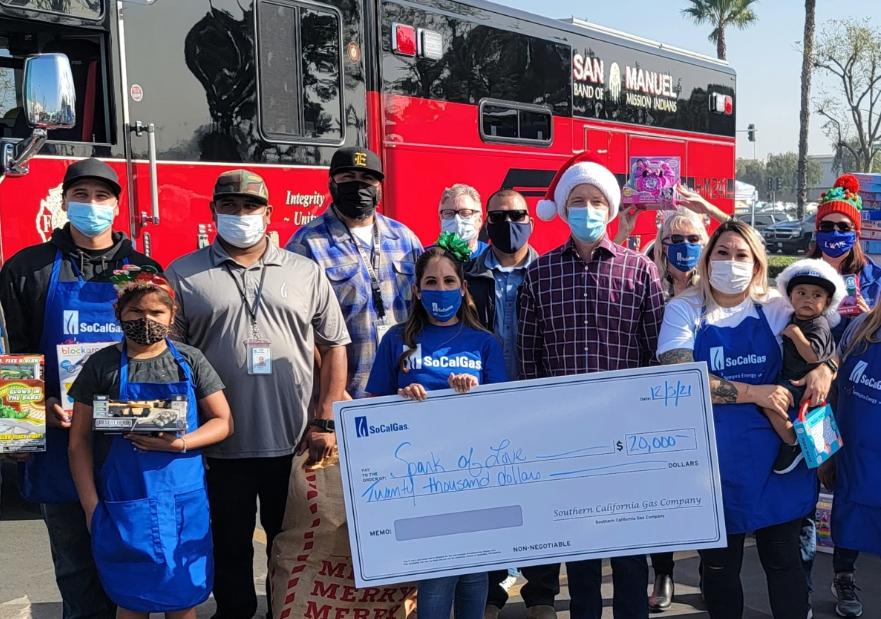 SoCalGas volunteers holding a giant check and toys posing for a photo
