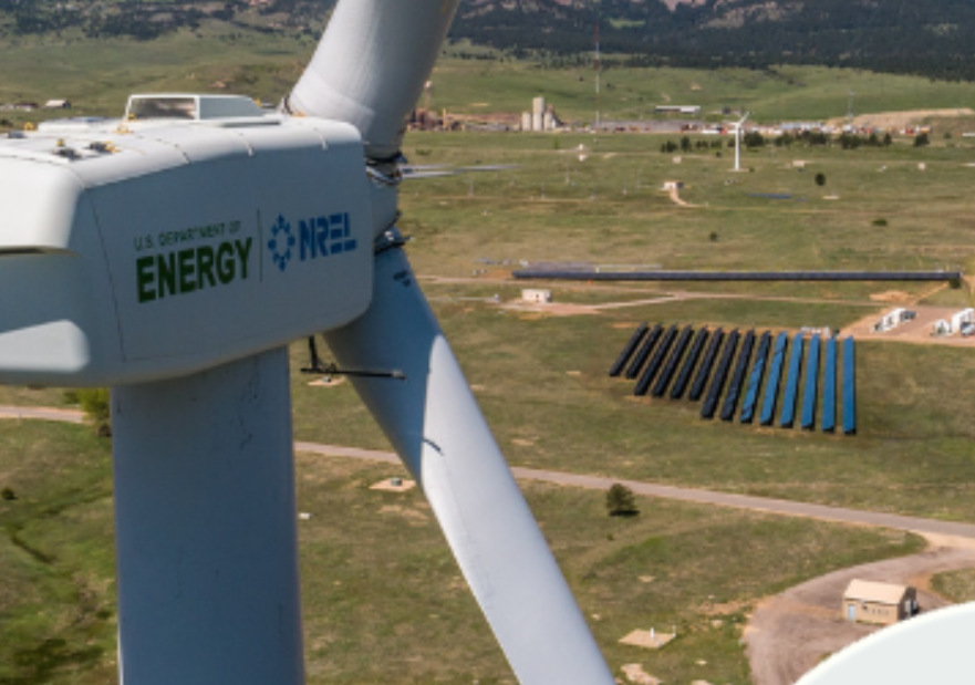 Image of a windmill at the propellers with solar panels in the distance on the ground below
