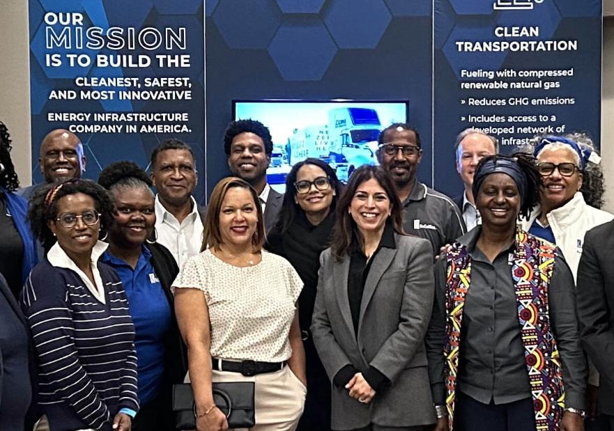 A group of people posing for a picture in front of the SoCalGas booth at the conference