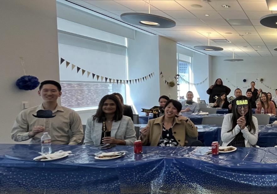 People in an office room holding miniature signs on sticks in front of their faces