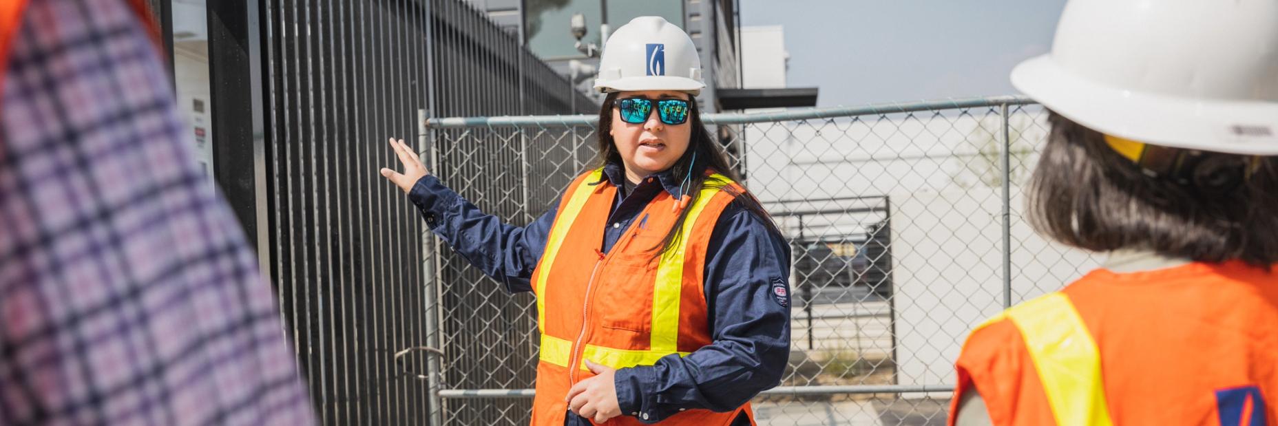 Jennifer Medina talking with employees in front of a gate the the hydrogen innovation experience