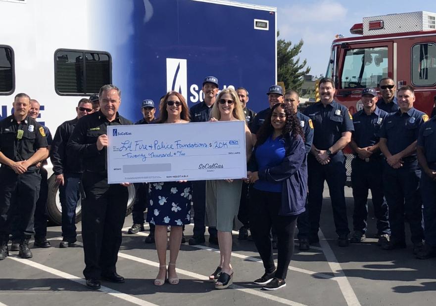 Police, Fire, and SoCalGas employees holding giant donation check