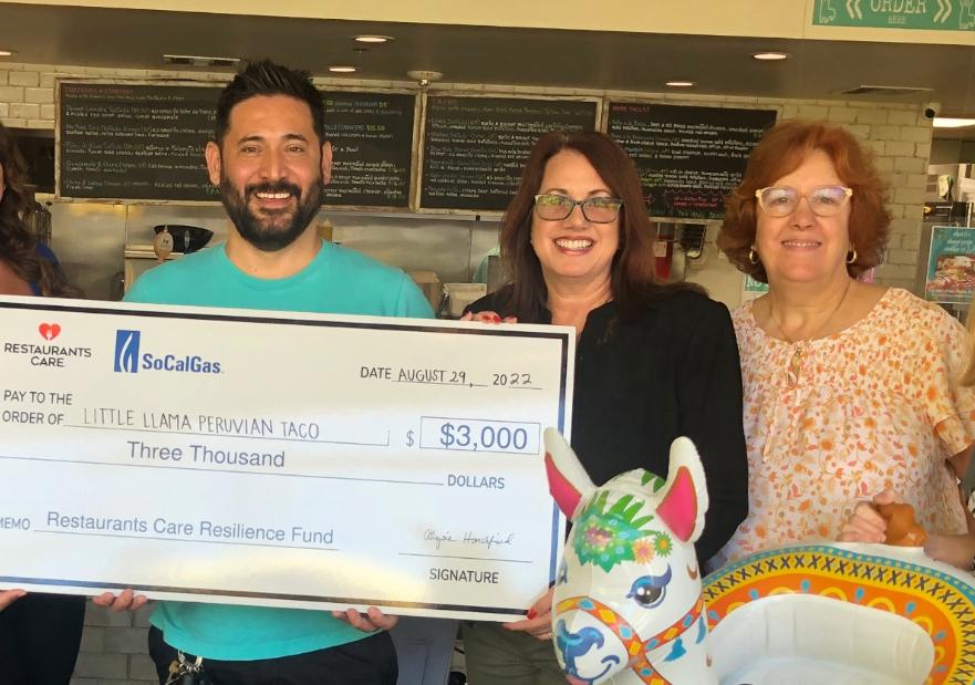 People holding a giant check and floaties for a pool at a restaurant
