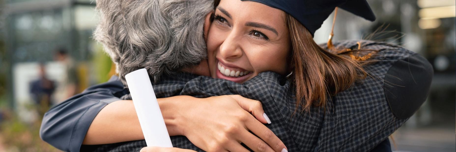 Graduate hugging loved one with diploma in hand