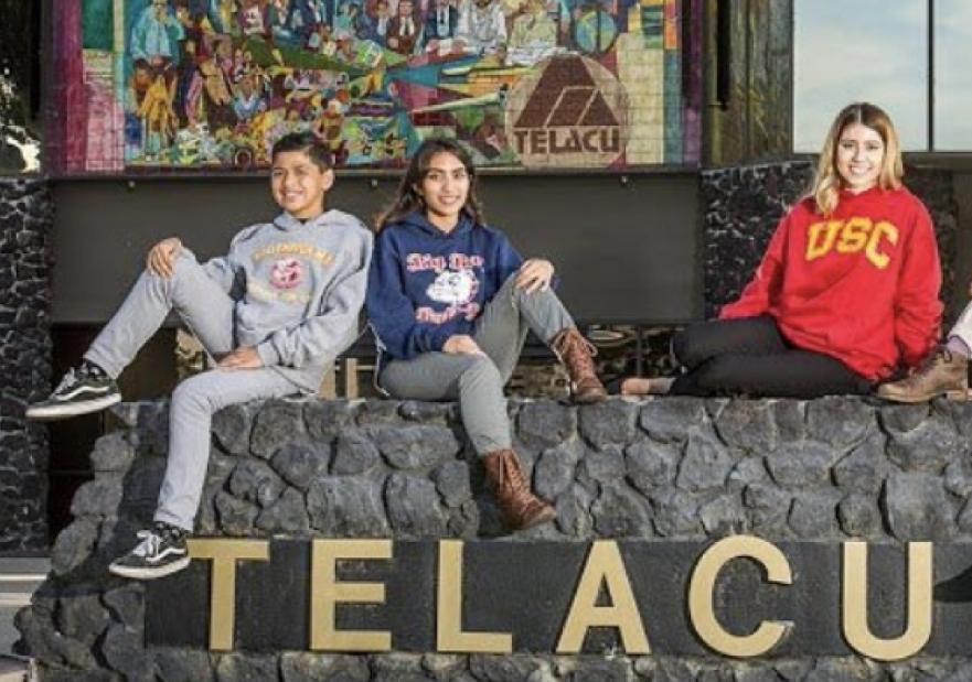 Students posing on the ledge about the TELACU CENTER lettering