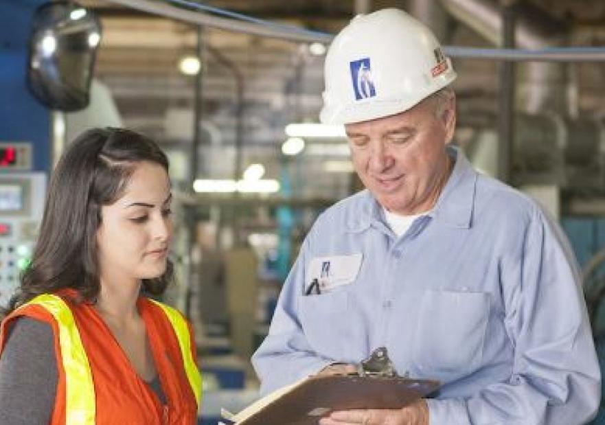 Two workers looking at a clipboard in a manufacturing setting