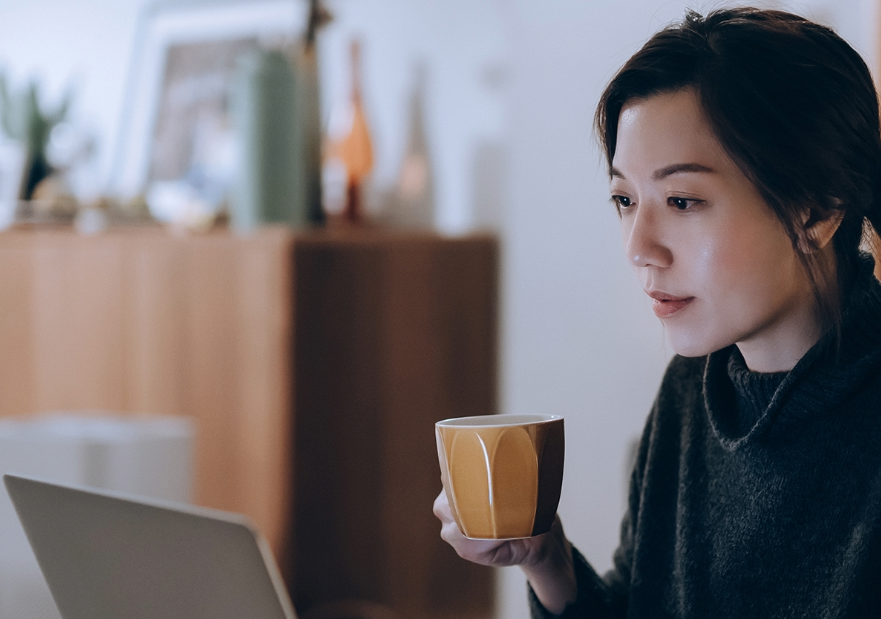 Lady drinking coffee and looking at her computer
