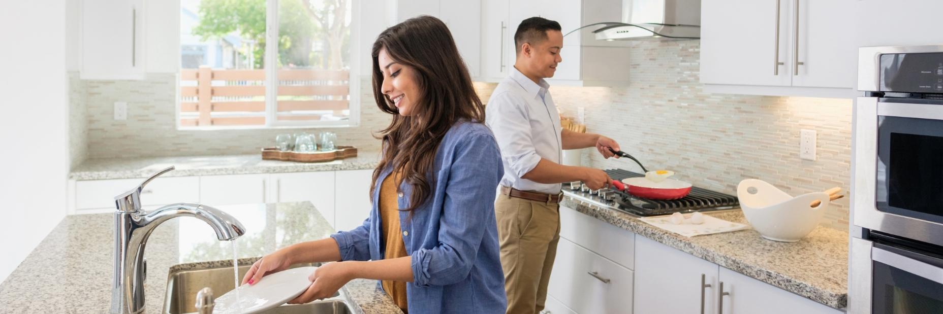 Couple in kitchen cooking and cleaning dishes