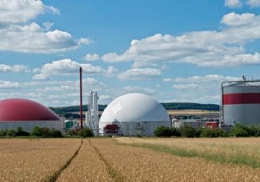 Renewable natural gas facility where waste is being turned into fuel with fields and a mostly sunny skie in the background