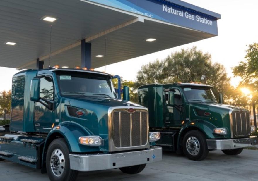 two natural gas trucks sitting at a filling station