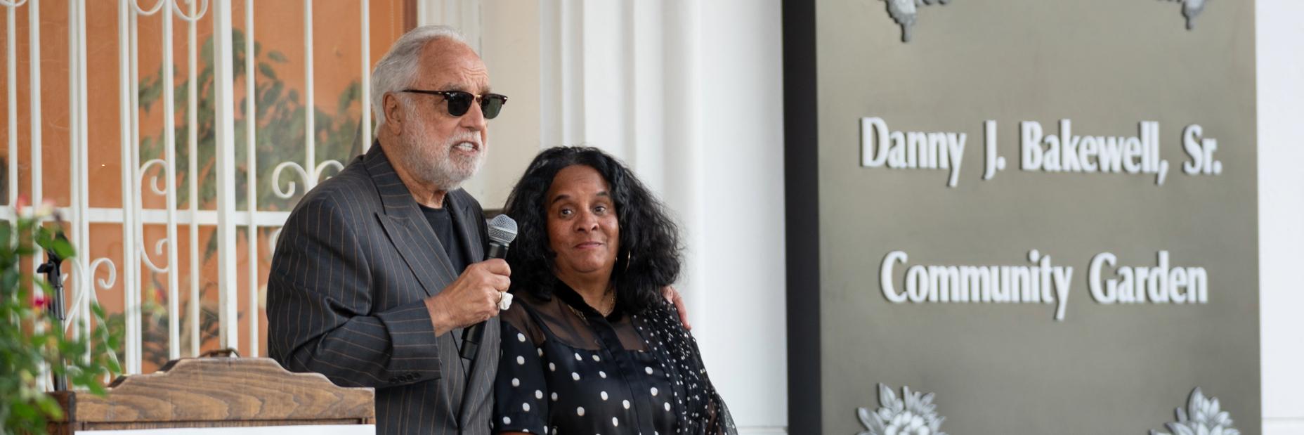 Man and woman speaking on microphone.