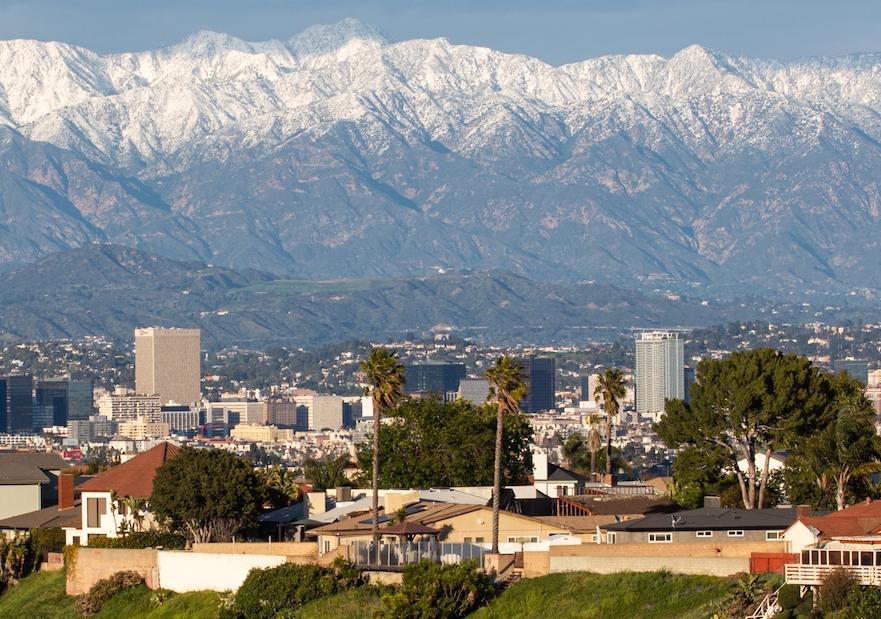 image of buildings in the foreground and snow capped mountains in the background